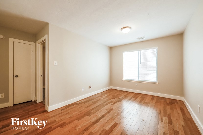 an empty living room with wood flooring and a window