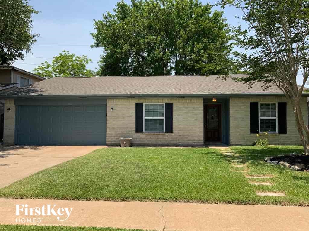 front view of a brick house with a lawn and a tree