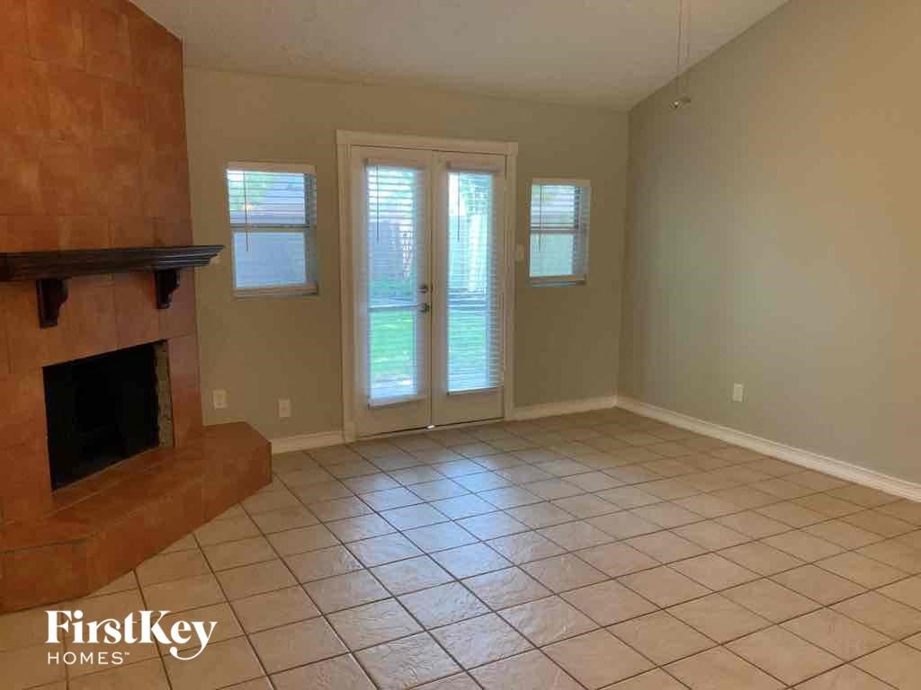 an empty living room with a fireplace and tiled floors