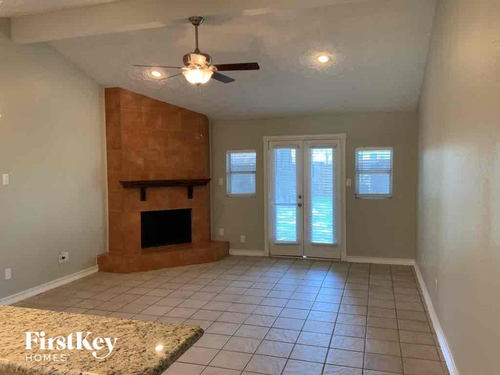 an empty living room with a fireplace and a ceiling fan