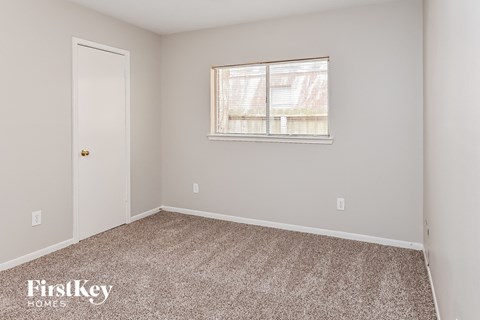 a bedroom with carpet and a window and a door