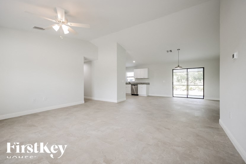 an empty living room with white walls and a ceiling fan