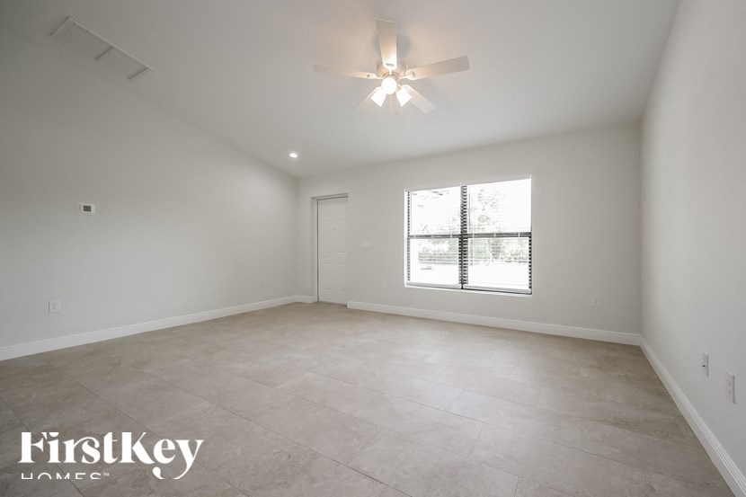an empty living room with a ceiling fan and a window
