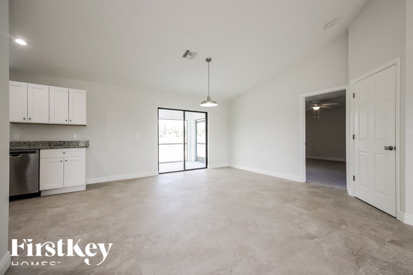 an empty kitchen and living room with white cabinets and white walls