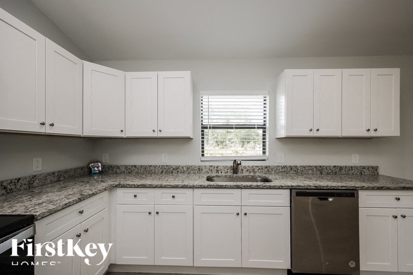 a white kitchen with granite counter tops and white cabinets