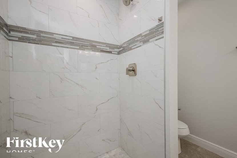 a white marble shower in a bathroom with a toilet