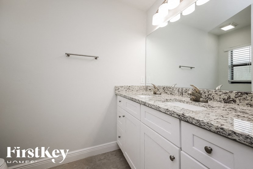 a bathroom with white cabinets and granite counter tops
