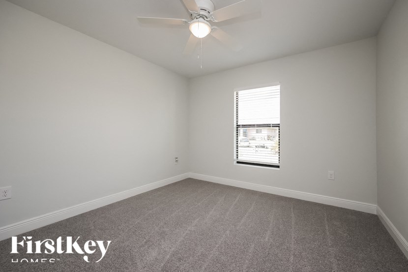 an empty room with a ceiling fan and a window
