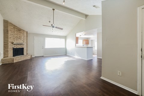 an empty living room with a fireplace and wood flooring