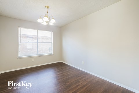 a bedroom with white walls and wood floors and a window