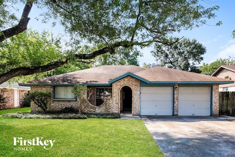 A house with a green roof and a garage door is for sale.
