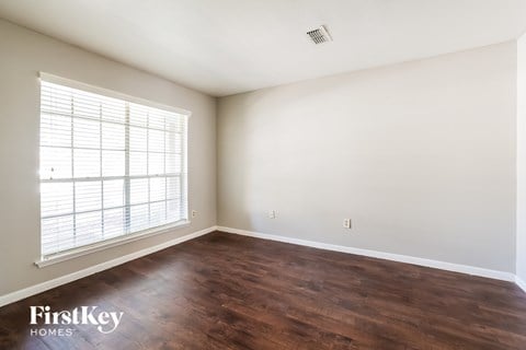 A room with wooden floors and a window with blinds.