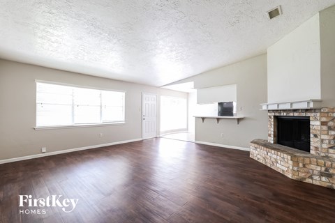 A room with a stone fireplace and wooden floors.