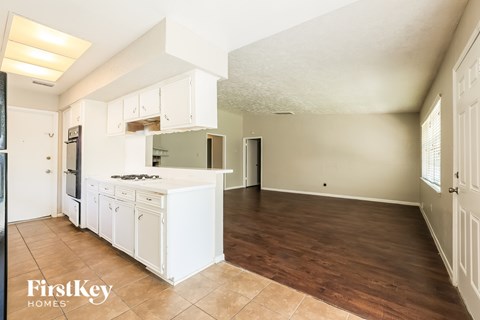 A kitchen with white cabinets and a wooden floor.