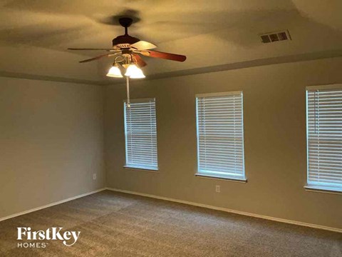 A room with a ceiling fan and two windows.