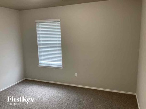 A room with a window and a carpeted floor.