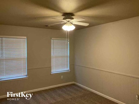A room with a ceiling fan and two windows.