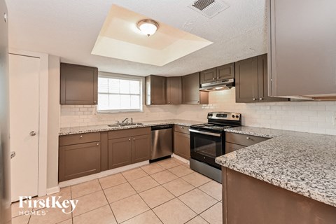 A kitchen with a granite counter top and a stainless steel oven.