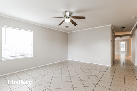 A spacious room with a ceiling fan and tiled flooring.