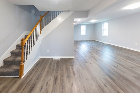A spacious room with wooden floors and a staircase with a wooden banister.