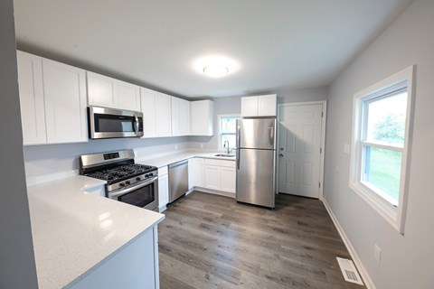 A kitchen with white cabinets and a stainless steel refrigerator.