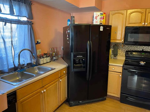 A black refrigerator in a kitchen with wooden cabinets.