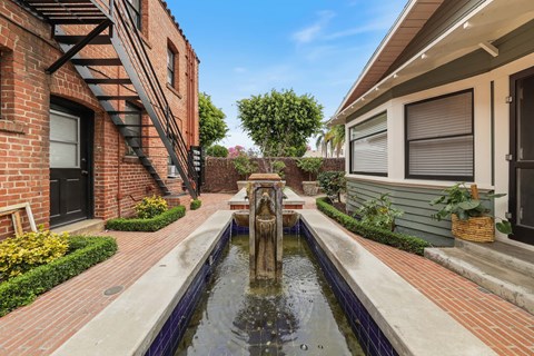 A brick building with a fountain in the middle of a walkway.