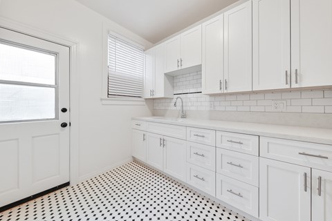 A kitchen with white cabinets and a black and white floor.