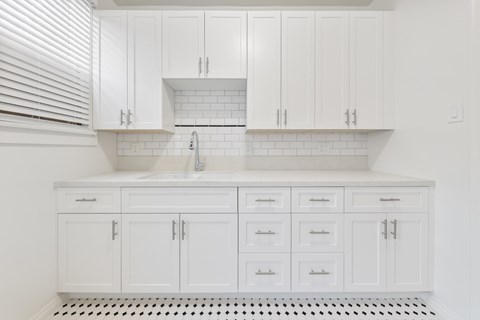 A kitchen with white cabinets and a white tiled backsplash.