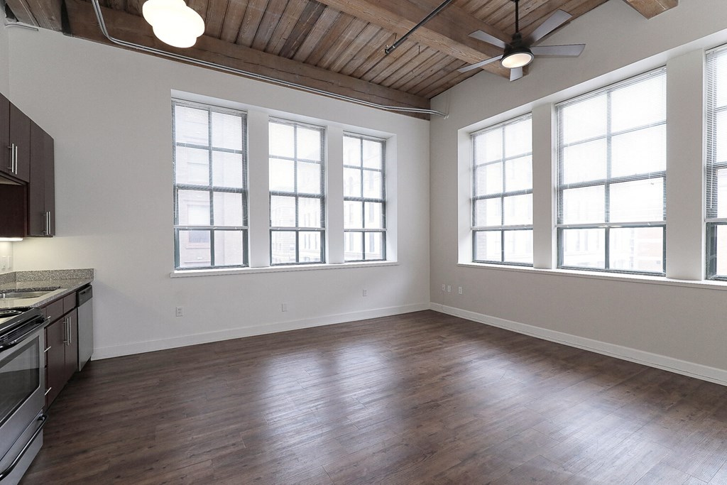 an empty kitchen and living room with wood floors and windows