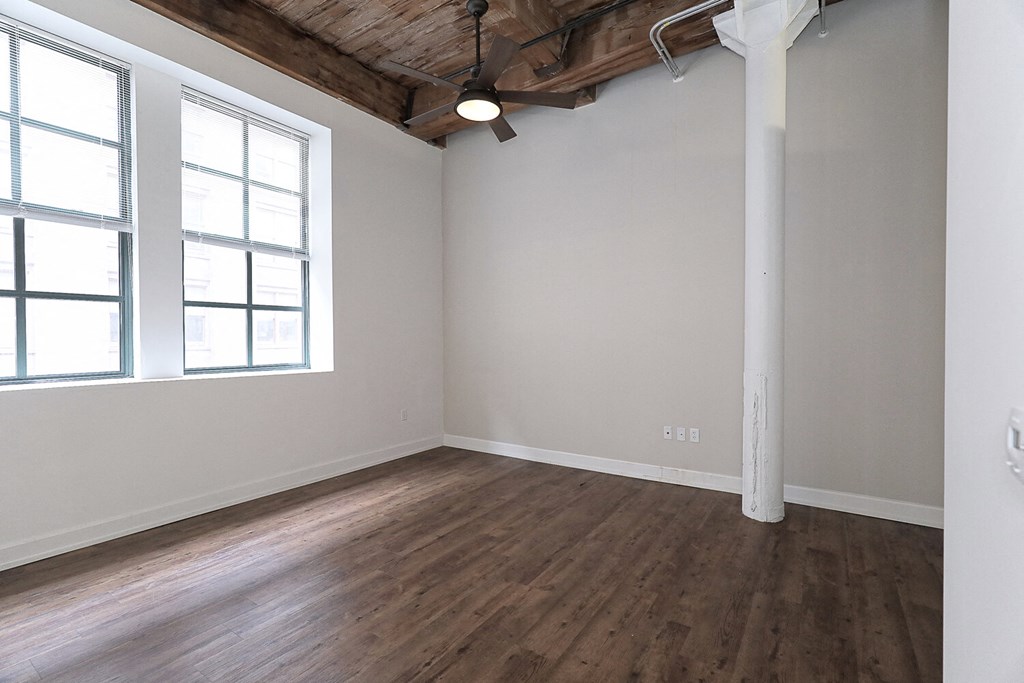 an empty living room with wood flooring and a large window