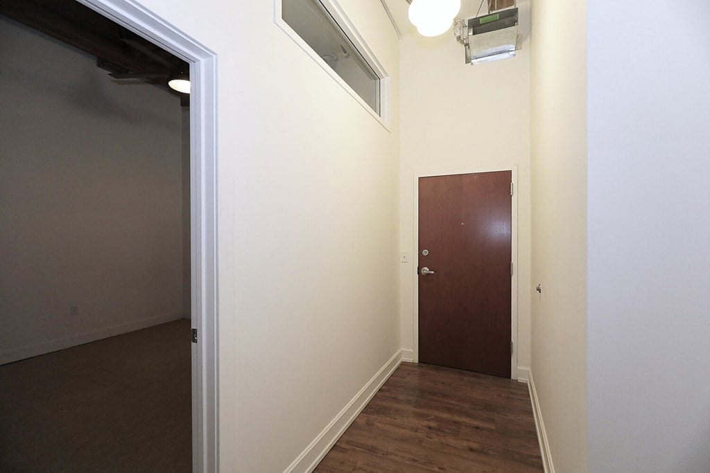 a room with a door and a hallway with a wood floor