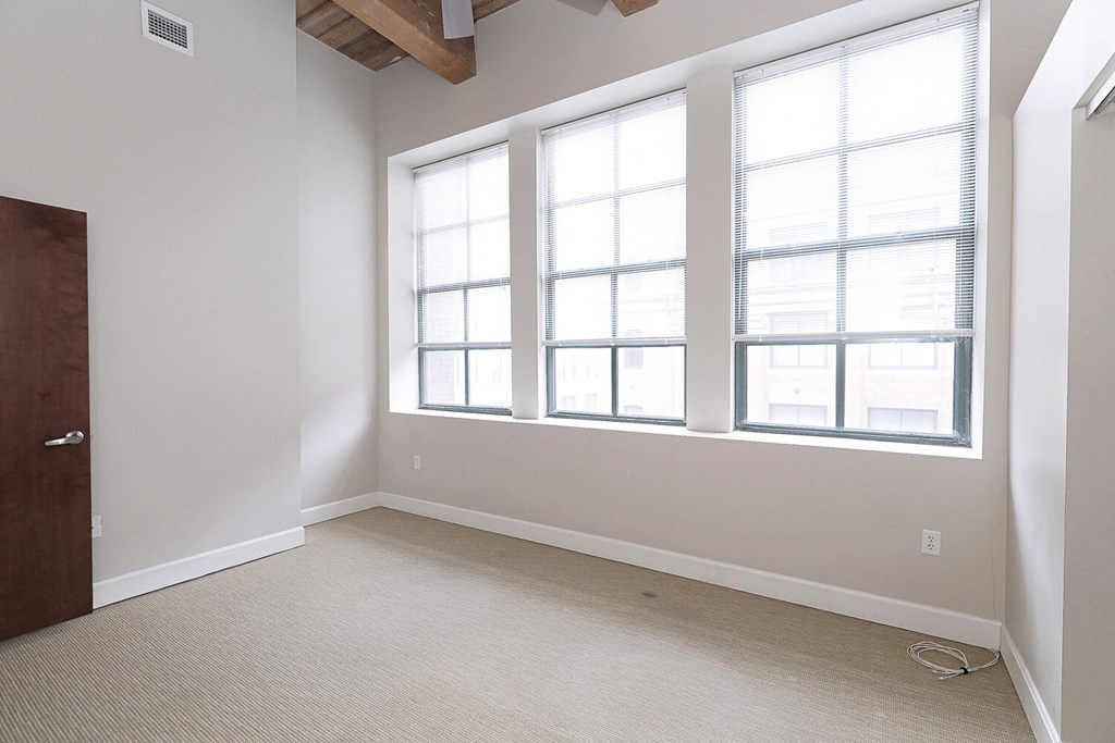 an empty room with three windows and a door