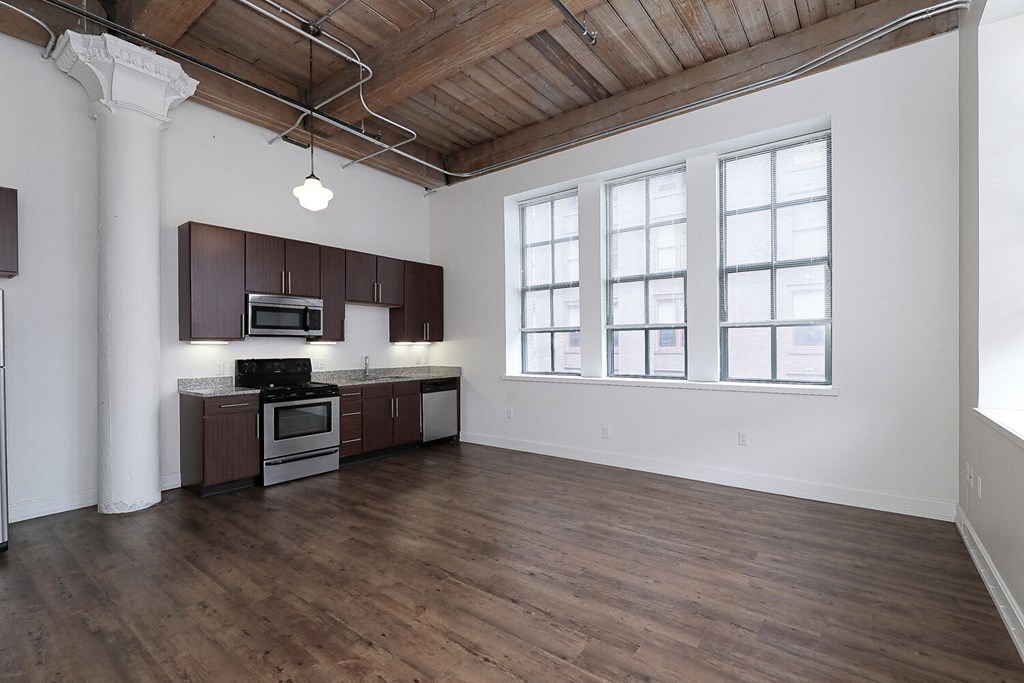 an open kitchen and living room with wood flooring and a large window