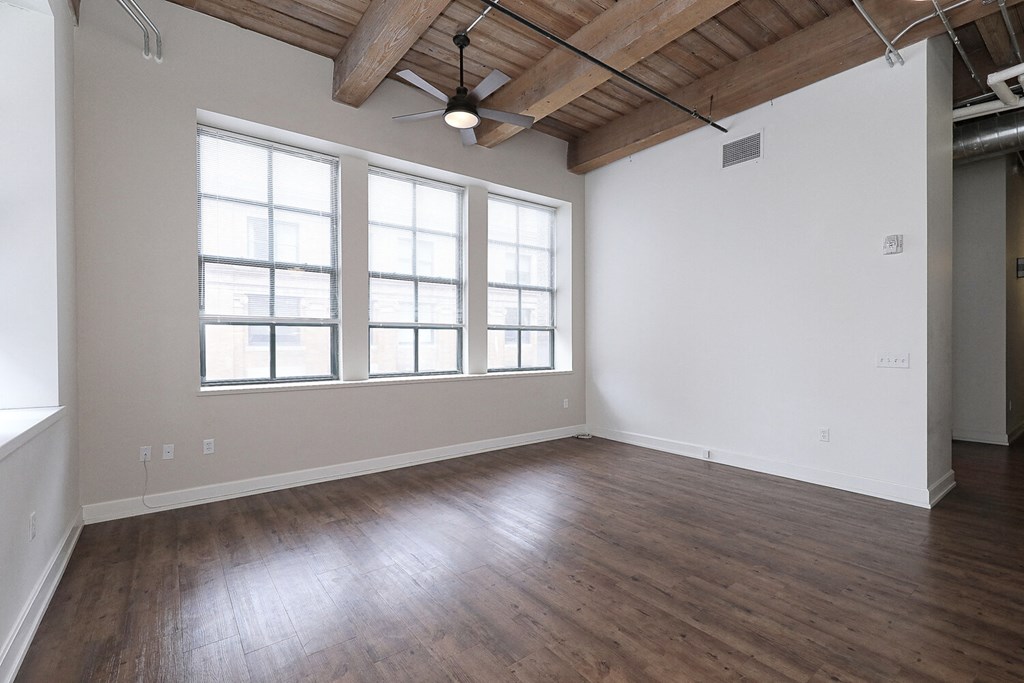 an empty living room with wood floors and a ceiling fan