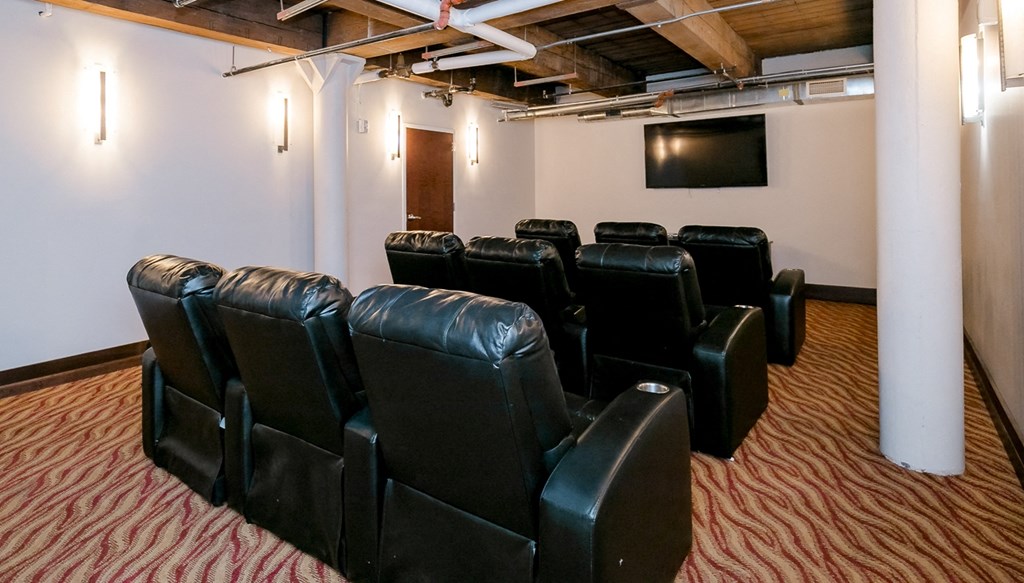 a theater room with black leather chairs and a television