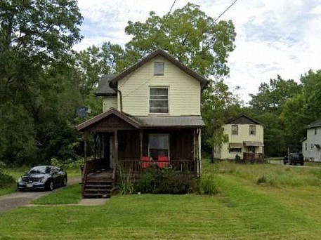 A small house with a porch and a car parked in front.