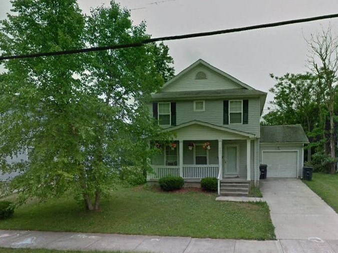 a house with a porch and a tree in front of it