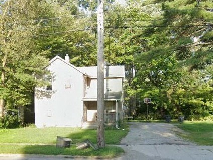 A white house is surrounded by trees and a grassy area.