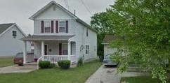 A white house with a red stripe on the window shutters.