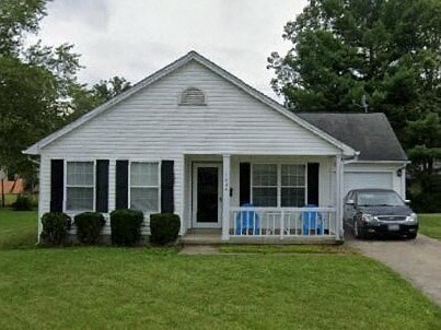 A small white house with a black car parked in front.