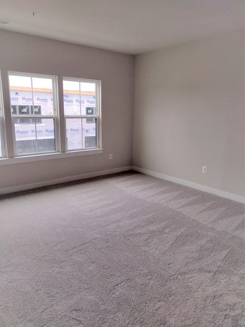 an empty living room with carpet and two windows