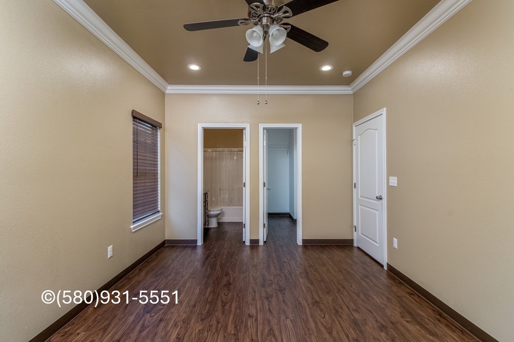 A room with a ceiling fan and wooden floors.