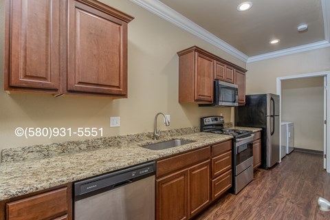 A kitchen with brown cabinets and granite countertops.