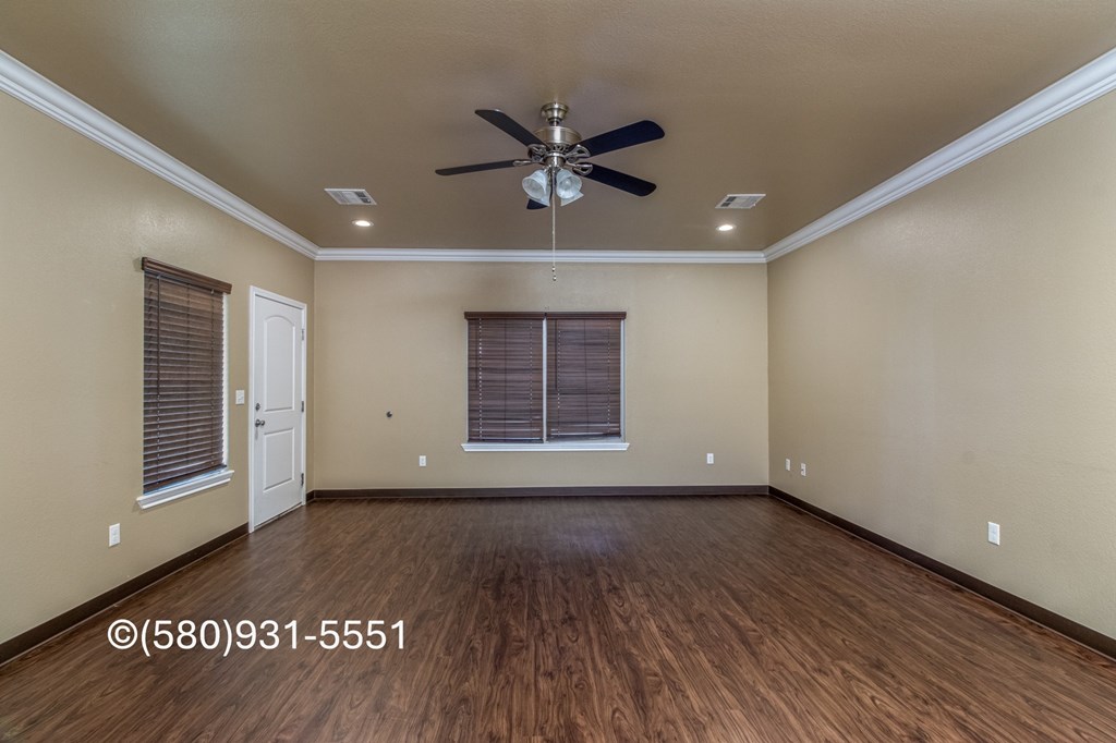 A room with a ceiling fan and wooden flooring.