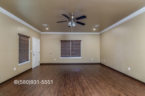 A room with a ceiling fan and wooden flooring.