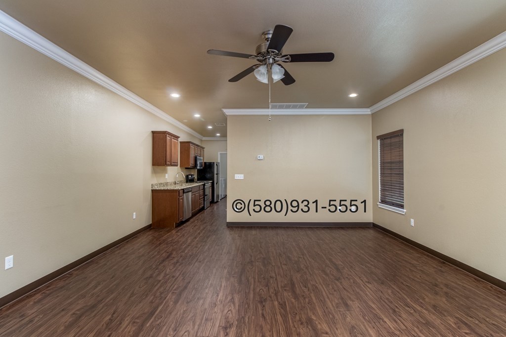 A spacious room with a ceiling fan and wooden flooring.