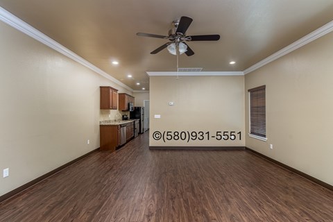 A spacious room with a ceiling fan and wooden flooring.