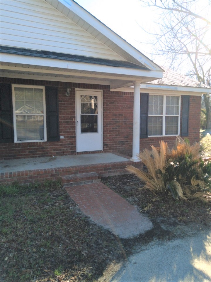 a front porch of a brick house with a white door
