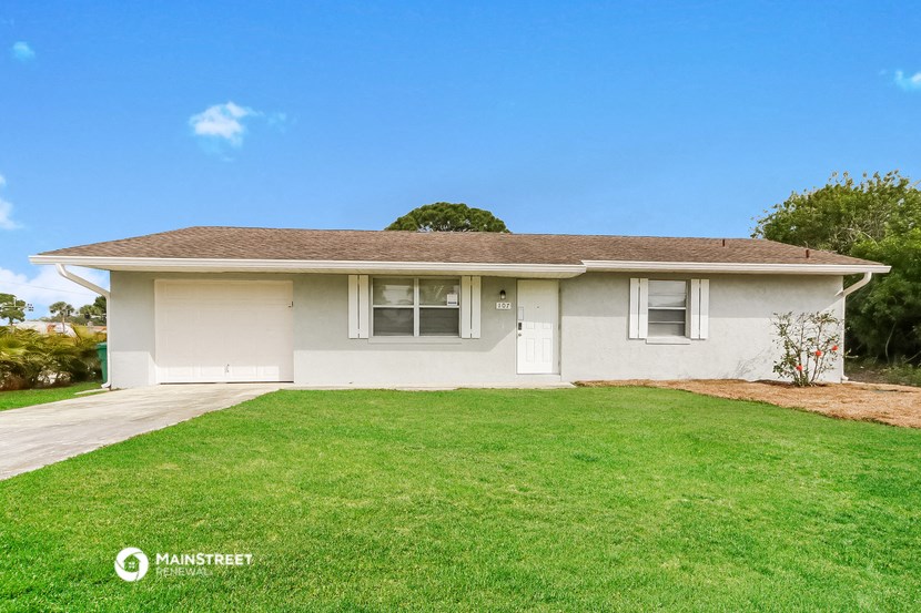 a white house with a grassy yard and a driveway